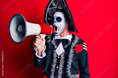 Scary man wearing day of the dead make up and costumbre from traditional ritual in Mexico shouting through megaphone