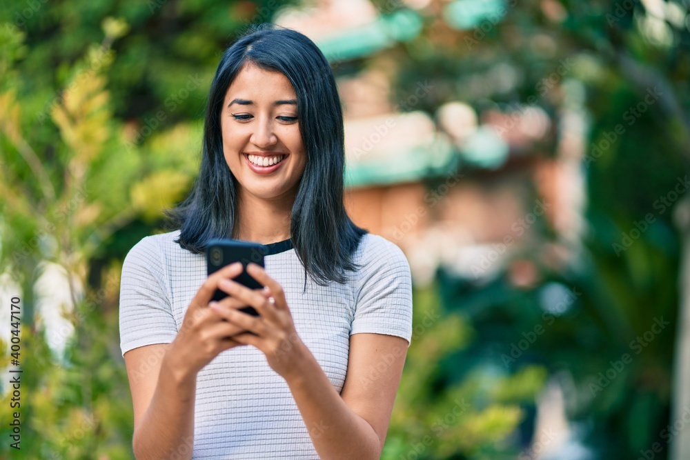 Young hispanic woman smiling happy using smartphone at the city. Young hispanic woman smiling happy using smartphone at the city.