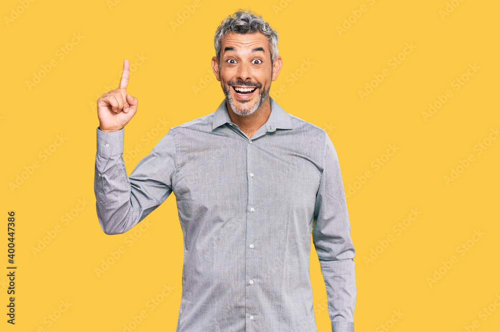 Middle age grey-haired man wearing casual clothes pointing finger up with successful idea. exited and happy. number one. Middle age grey-haired man wearing casual clothes pointing finger up with successful idea. exited and happy. number one.