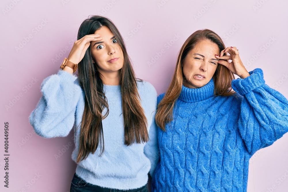 Hispanic family of mother and daughter wearing wool winter sweater worried and stressed about a problem with hand on forehead, nervous and anxious for crisis Hispanic family of mother and daughter wearing wool winter sweater worried and stressed about a problem with hand on forehead, nervous and anxious for crisis