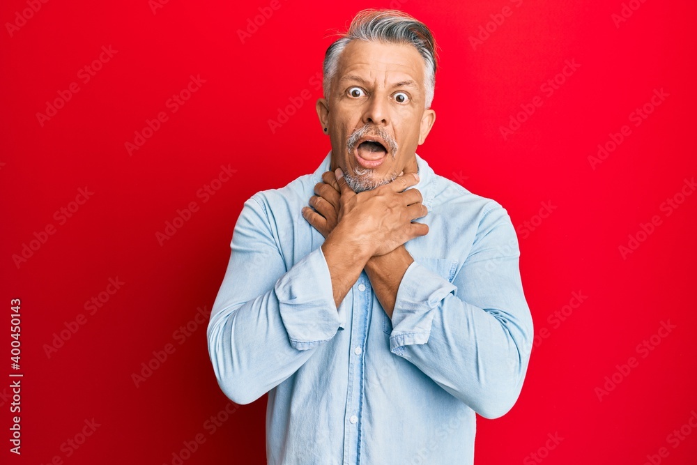 Middle age grey-haired man wearing casual clothes shouting and suffocate because painful strangle. health problem. asphyxiate and suicide concept. Middle age grey-haired man wearing casual clothes shouting and suffocate because painful strangle. health problem. asphyxiate and suicide concept.