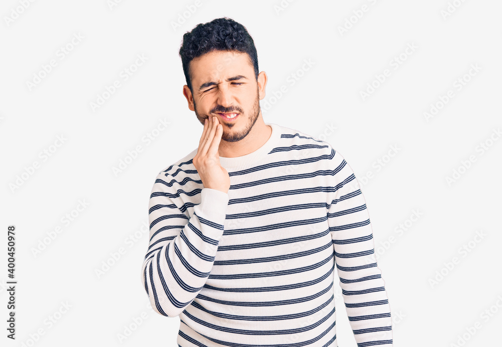 Young hispanic man wearing casual clothes touching mouth with hand with painful expression because of toothache or dental illness on teeth. dentist Young hispanic man wearing casual clothes touching mouth with hand with painful expression because of toothache or dental illness on teeth. dentist