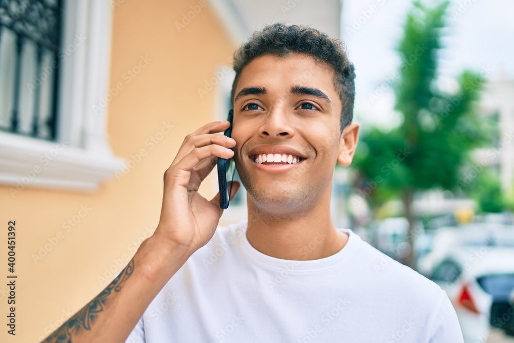 Young latin man smiling happy talking on the smartphone walking at the city. Young latin man smiling happy talking on the smartphone walking at the city.