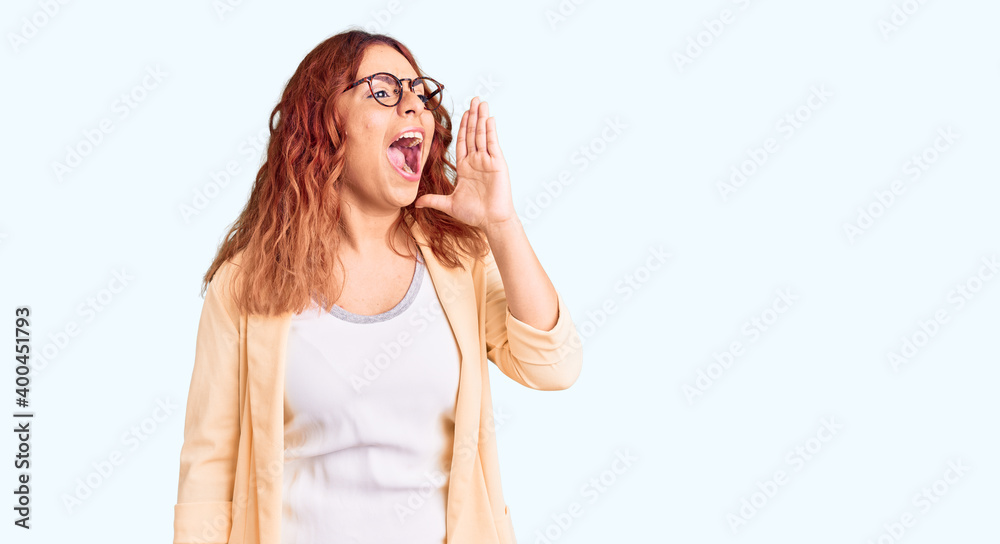 Young latin woman wearing business clothes shouting and screaming loud to side with hand on mouth. communication concept.
