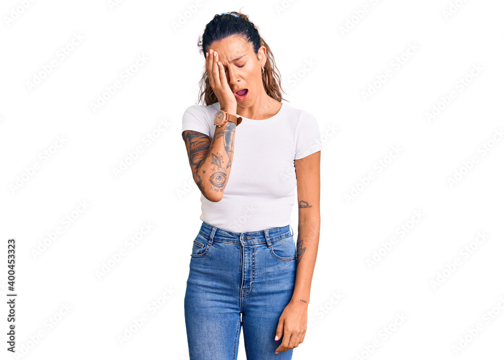 Young hispanic woman with tattoo wearing casual white tshirt yawning tired covering half face, eye and mouth with hand. face hurts in pain.