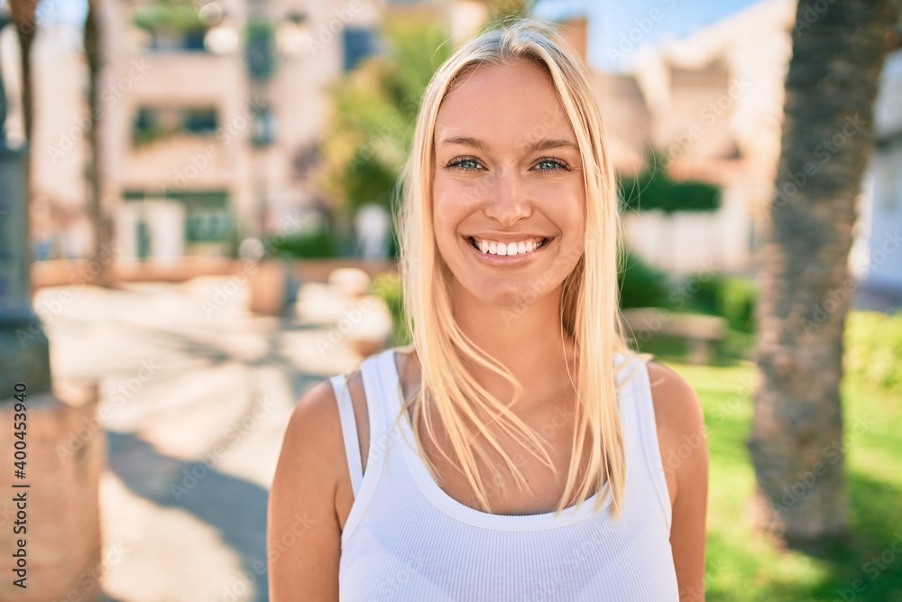 Young blonde girl smiling happy walking at the park.
