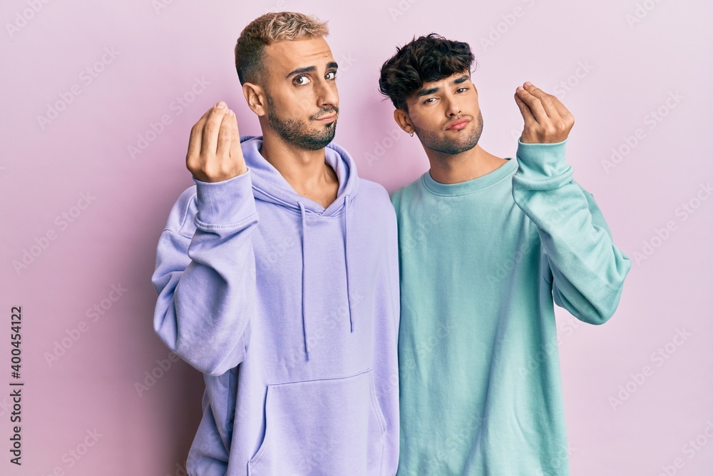 Homosexual gay couple standing together wearing casual clothes doing italian gesture with hand and fingers confident expression Homosexual gay couple standing together wearing casual clothes doing italian gesture with hand and fingers confident expression