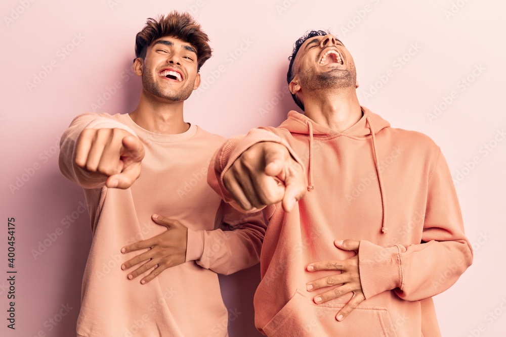 Young gay couple wearing casual clothes laughing at you, pointing finger to the camera with hand over body, shame expression Young gay couple wearing casual clothes laughing at you, pointing finger to the camera with hand over body, shame expression