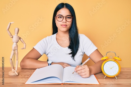 Young beautiful asian girl sitting on the table stuying for university thinking attitude and sober expression looking self confident photo