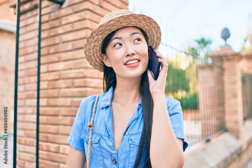 Young chinese tourist woman talking on the smartphone at street of city.