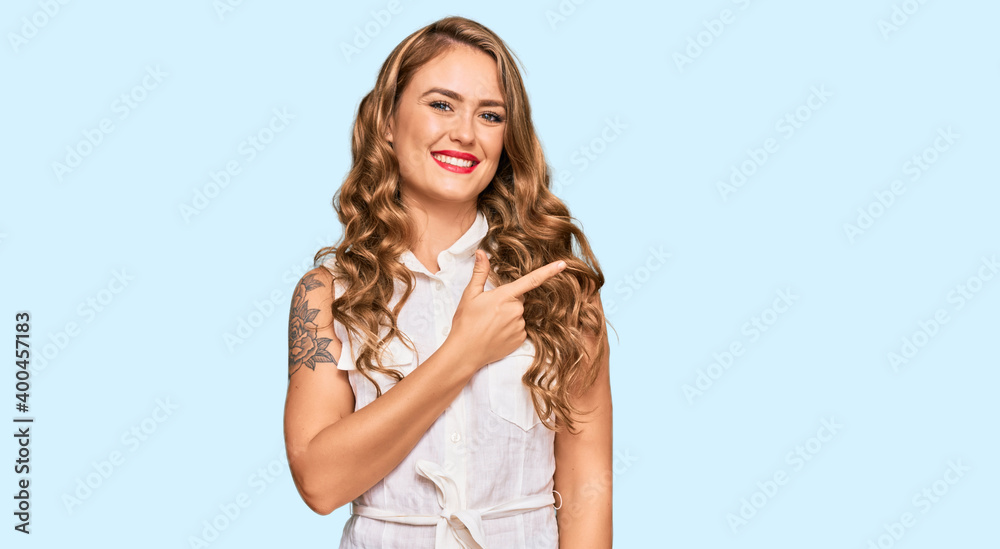 Young blonde girl wearing casual clothes cheerful with a smile of face pointing with hand and finger up to the side with happy and natural expression on face Young blonde girl wearing casual clothes cheerful with a smile of face pointing with hand and finger up to the side with happy and natural expression on face