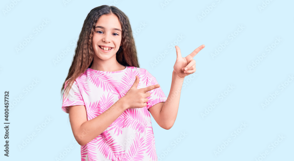 Cute hispanic child girl wearing casual clothes smiling and looking at the camera pointing with two hands and fingers to the side.