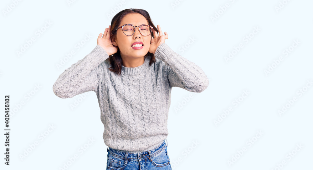 Young beautiful chinese girl wearing casual clothes trying to hear both hands on ear gesture, curious for gossip. hearing problem, deaf Young beautiful chinese girl wearing casual clothes trying to hear both hands on ear gesture, curious for gossip. hearing problem, deaf