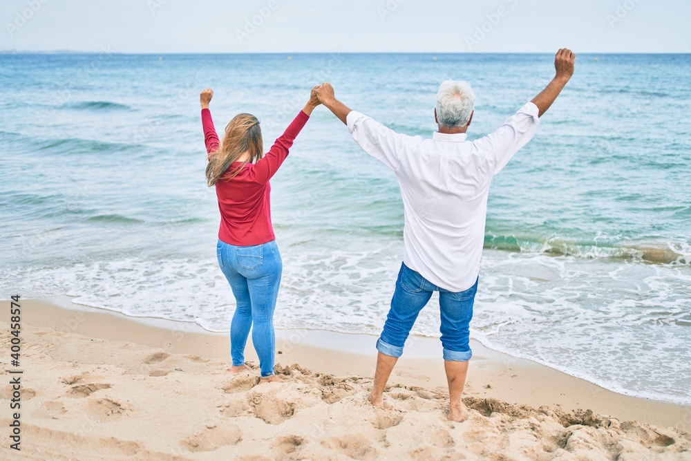 Middle age hispanic couple breathing with arms raised at the beach. Middle age hispanic couple breathing with arms raised at the beach.