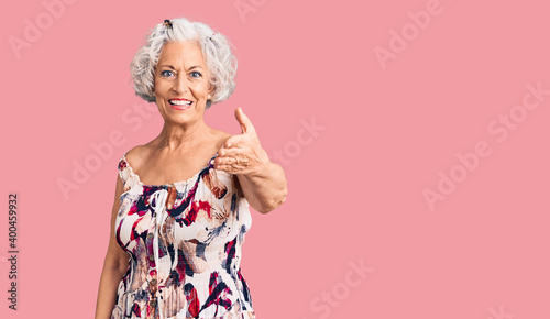 Senior grey-haired woman wearing casual clothes smiling friendly offering handshake as greeting and welcoming. successful business.