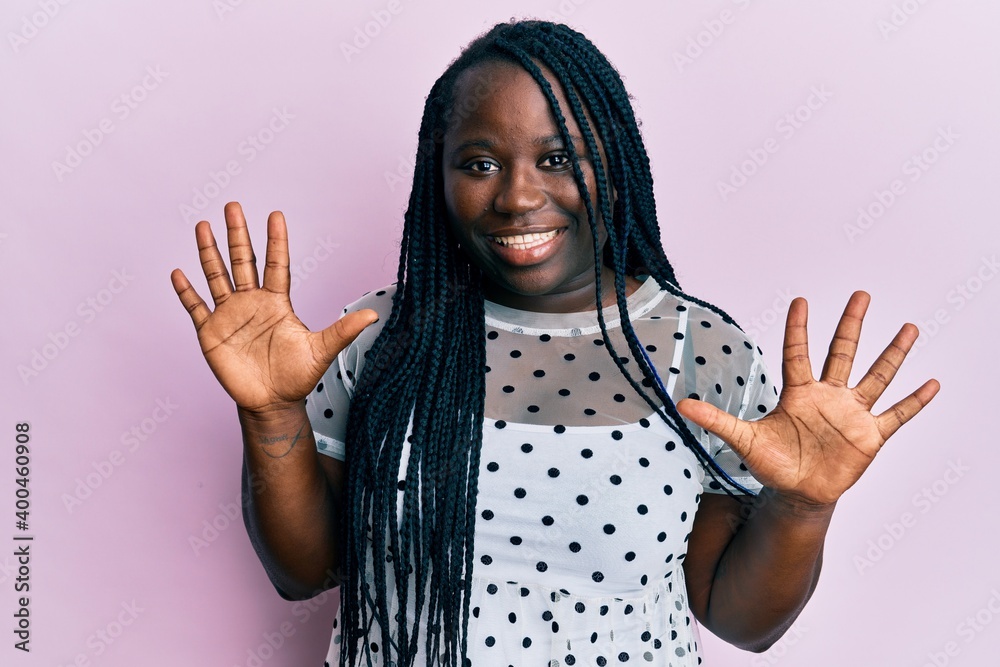 Young black woman with braids wearing casual clothes showing and pointing up with fingers number ten while smiling confident and happy. Young black woman with braids wearing casual clothes showing and pointing up with fingers number ten while smiling confident and happy.