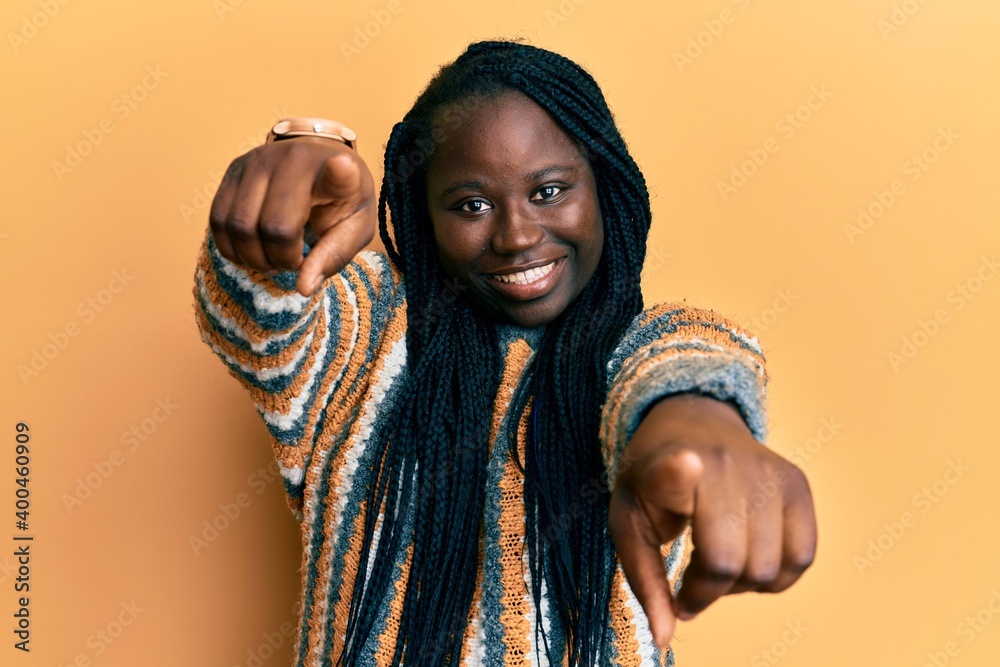 Young black woman with braids wearing casual winter sweater pointing to you and the camera with fingers, smiling positive and cheerful