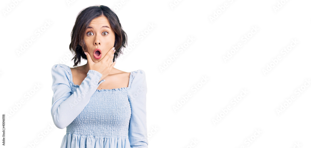 Young beautiful girl wearing casual clothes looking fascinated with disbelief, surprise and amazed expression with hands on chin Young beautiful girl wearing casual clothes looking fascinated with disbelief, surprise and amazed expression with hands on chin