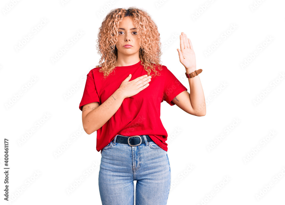 Young blonde woman with curly hair wearing casual red tshirt swearing with hand on chest and open palm, making a loyalty promise oath Young blonde woman with curly hair wearing casual red tshirt swearing with hand on chest and open palm, making a loyalty promise oath