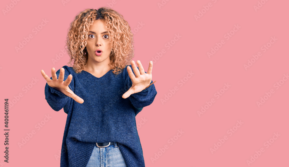 Obraz premium Young blonde woman with curly hair wearing casual winter sweater doing stop gesture with hands palms, angry and frustration expression