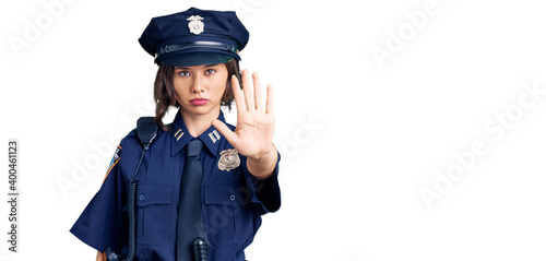 Young beautiful girl wearing police uniform doing stop sing with palm of the hand. warning expression with negative and serious gesture on the face.