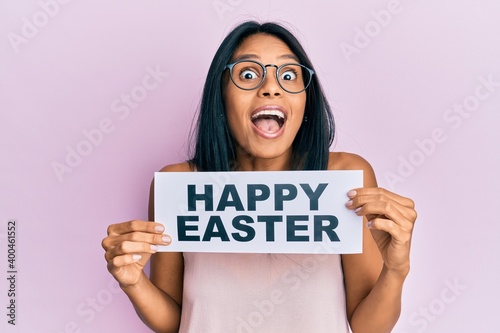 Young african american woman holding happy easter message paper celebrating crazy and amazed for success with open eyes screaming excited.