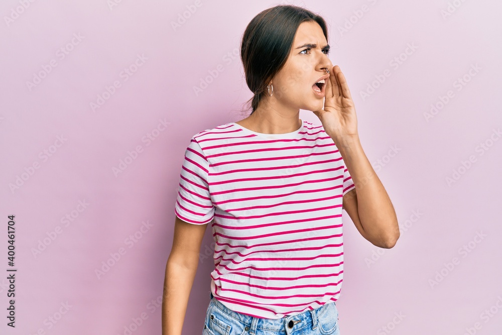 Young hispanic woman wearing casual clothes shouting and screaming loud to side with hand on mouth. communication concept. Young hispanic woman wearing casual clothes shouting and screaming loud to side with hand on mouth. communication concept.