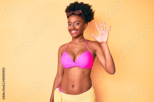 Young african american woman wearing bikini showing and pointing up with fingers number five while smiling confident and happy.