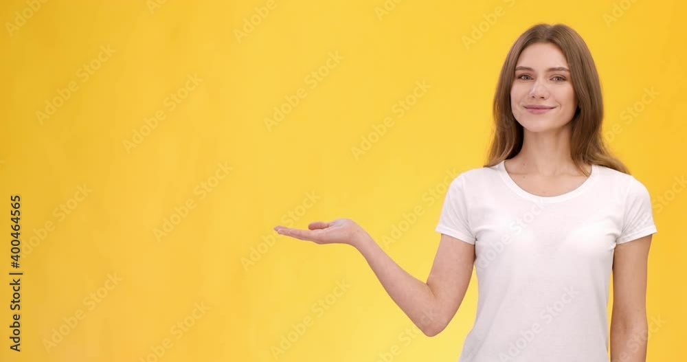 Young cheerful lady stretching hand aside, showing advertisement, empty space for mockup, orange background Young cheerful lady stretching hand aside, showing advertisement, empty space for mockup, orange background