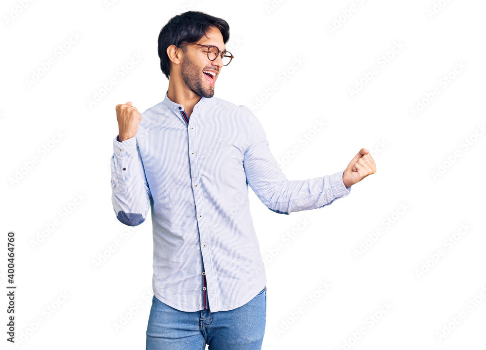 Handsome hispanic man wearing business shirt and glasses dancing happy and cheerful, smiling moving casual and confident listening to music Handsome hispanic man wearing business shirt and glasses dancing happy and cheerful, smiling moving casual and confident listening to music