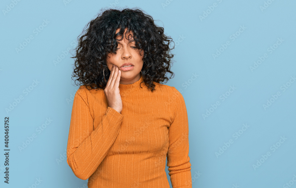 Young hispanic woman wearing casual clothes touching mouth with hand with painful expression because of toothache or dental illness on teeth. dentist