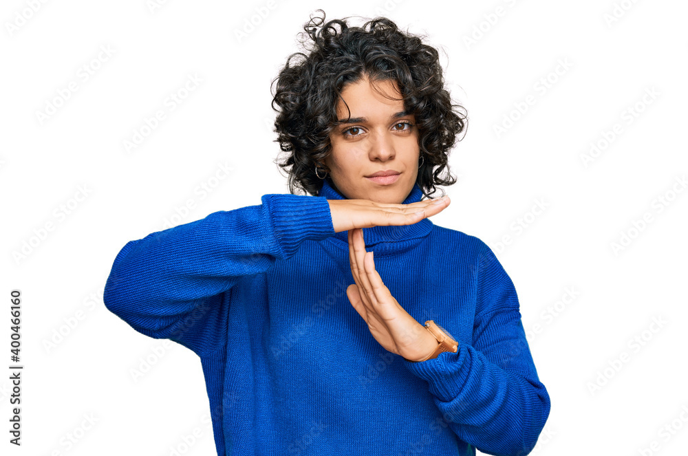 Young hispanic woman with curly hair wearing turtleneck sweater doing time out gesture with hands, frustrated and serious face Young hispanic woman with curly hair wearing turtleneck sweater doing time out gesture with hands, frustrated and serious face