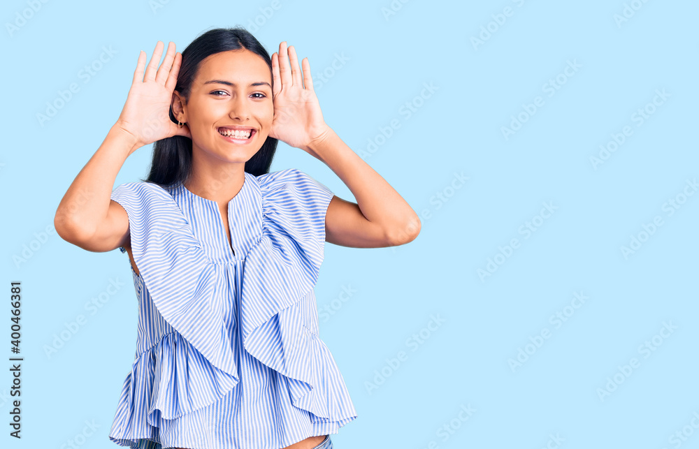 Young beautiful latin girl wearing casual clothes smiling cheerful playing peek a boo with hands showing face. surprised and exited Young beautiful latin girl wearing casual clothes smiling cheerful playing peek a boo with hands showing face. surprised and exited
