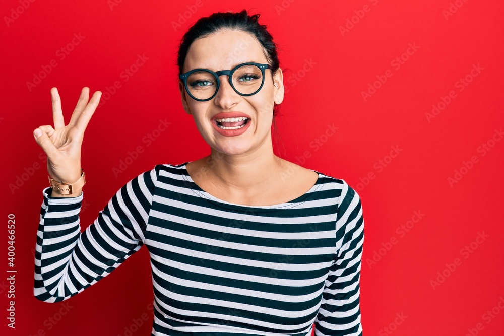 Young caucasian woman wearing casual clothes and glasses showing and pointing up with fingers number three while smiling confident and happy. Young caucasian woman wearing casual clothes and glasses showing and pointing up with fingers number three while smiling confident and happy.