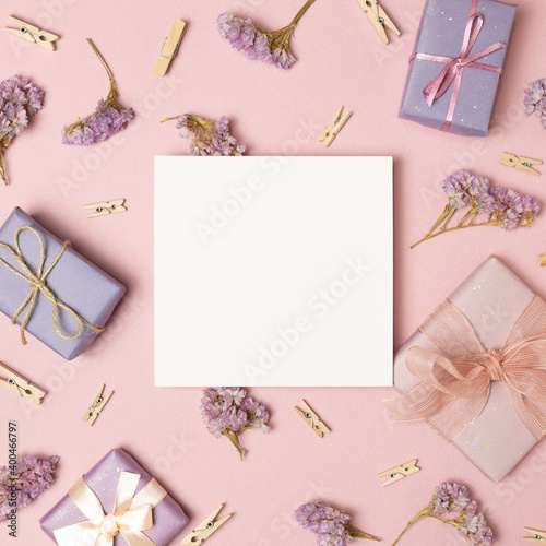 Empty memo paper with gift boxes, dry flowers, wooden clips on pink background. flat lay, top view, copy space