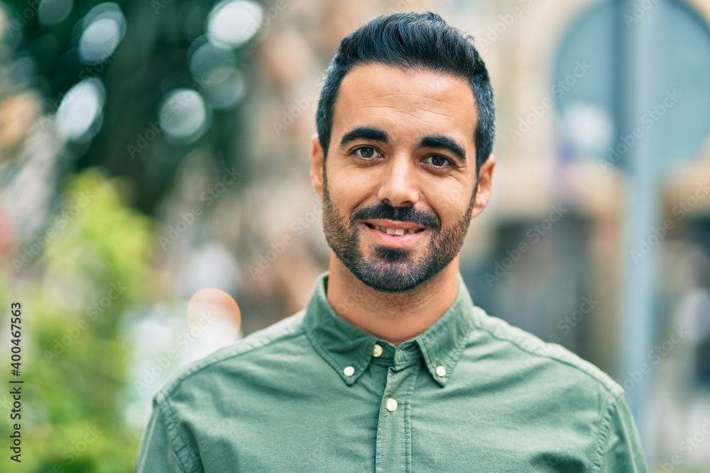 Naklejka premium Young hispanic man smiling happy standing at the city.