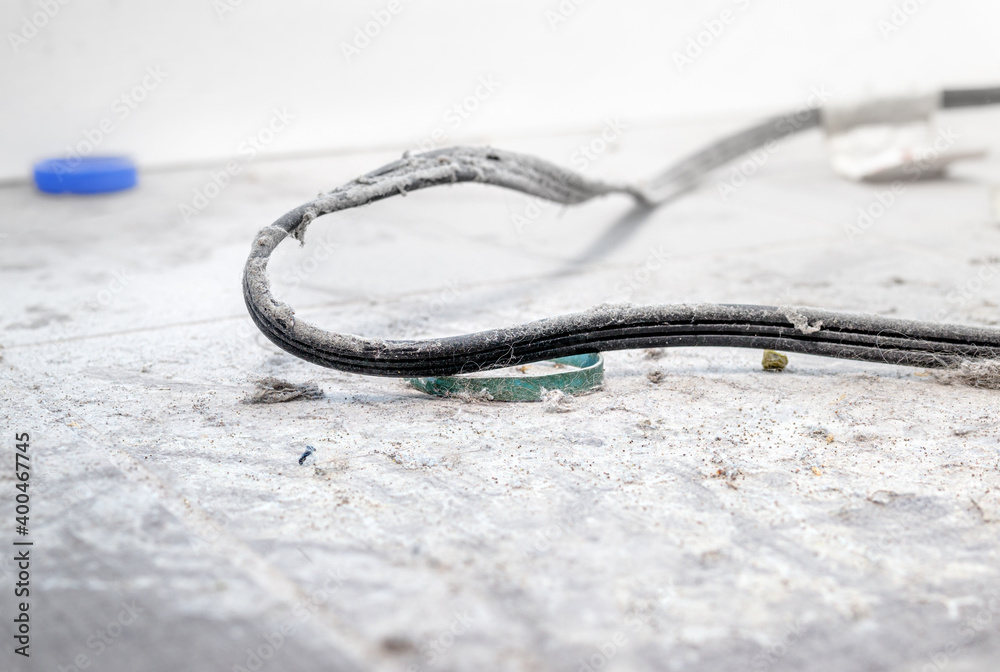 Thick layer of dust behind fridge or appliance. Close up of tiles, cable and rubber band caked in years of dust. Concept spring cleaning, overdue cleaning or dust allergy prevention. Selective focus.