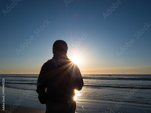 silhouette of a person on the beach at sunset © tawat