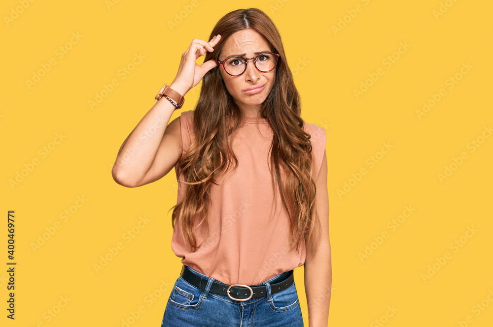 Young hispanic woman wearing casual clothes and glasses worried and stressed about a problem with hand on forehead, nervous and anxious for crisis