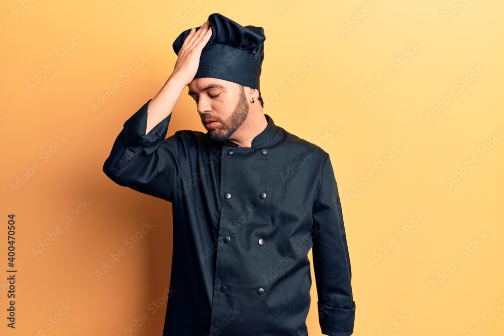 Young hispanic man wearing cooker uniform surprised with hand on head for mistake, remember error. forgot, bad memory concept. Young hispanic man wearing cooker uniform surprised with hand on head for mistake, remember error. forgot, bad memory concept.