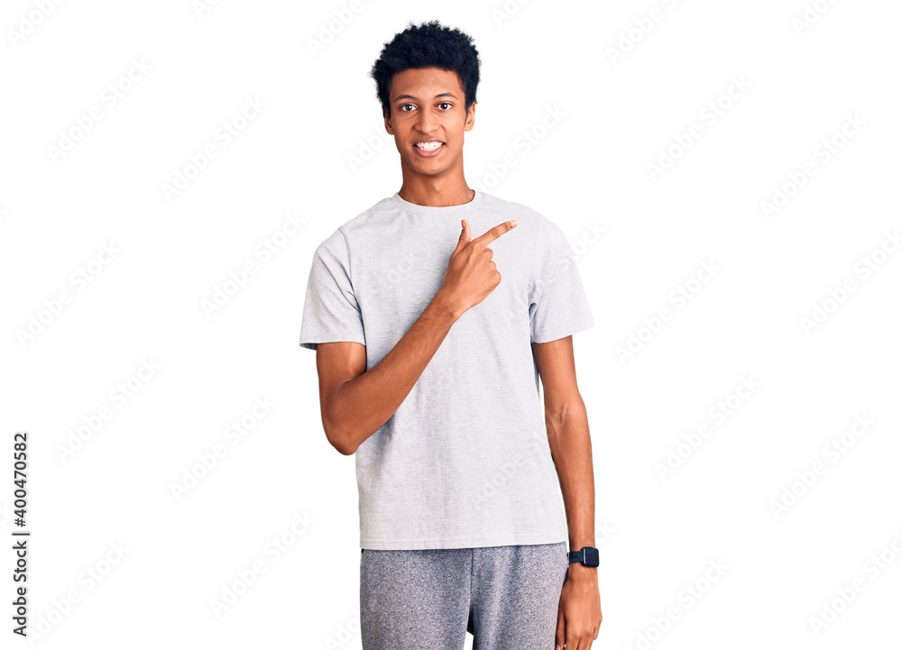 Fototapeta premium Young african american man wearing casual clothes cheerful with a smile of face pointing with hand and finger up to the side with happy and natural expression on face