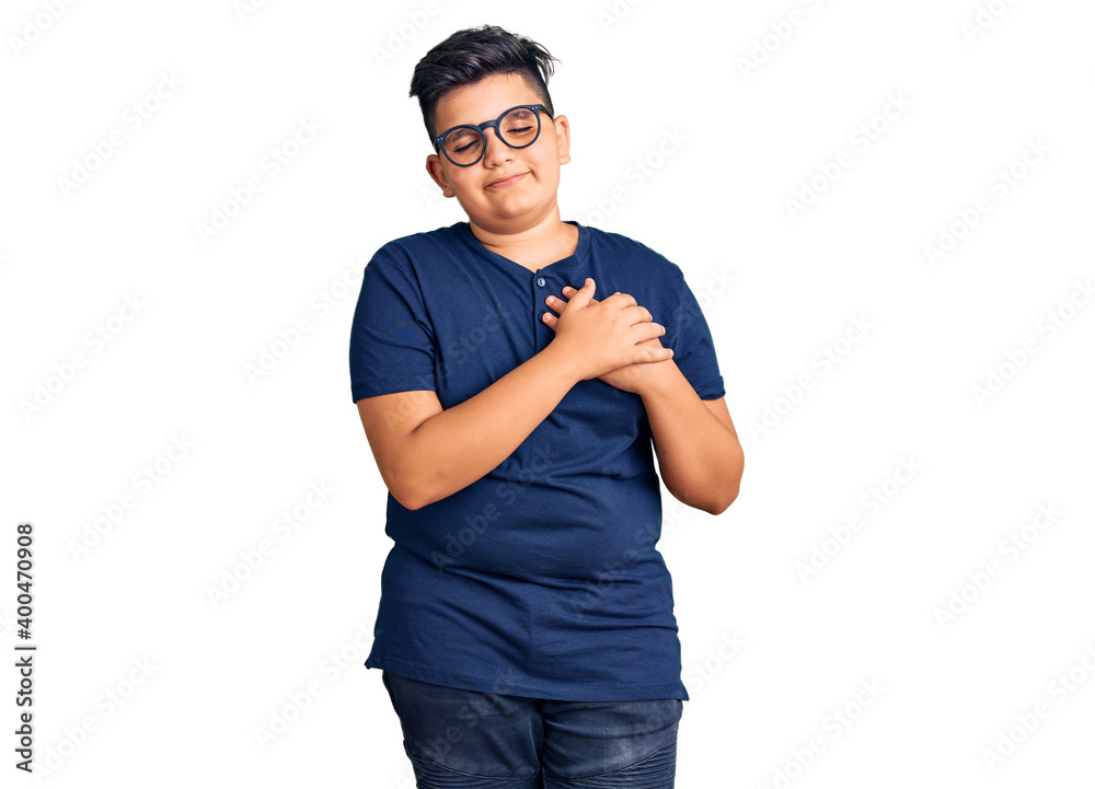 Little boy kid wearing casual clothes and glasses smiling with hands on chest with closed eyes and grateful gesture on face. health concept. Little boy kid wearing casual clothes and glasses smiling with hands on chest with closed eyes and grateful gesture on face. health concept.