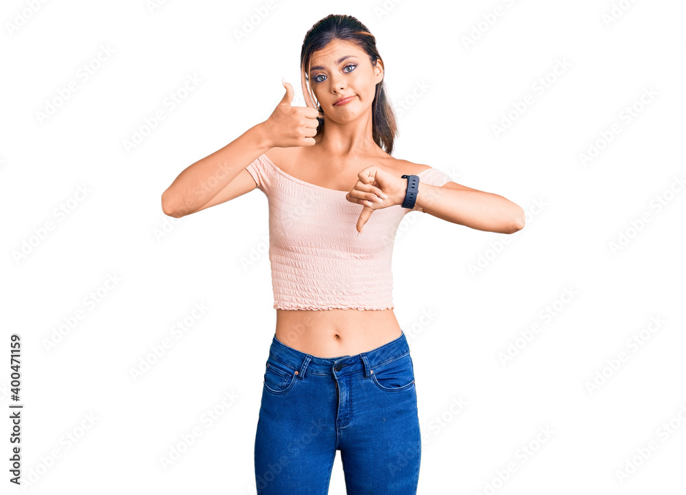 Young beautiful woman wearing casual clothes doing thumbs up and down, disagreement and agreement expression. crazy conflict Young beautiful woman wearing casual clothes doing thumbs up and down, disagreement and agreement expression. crazy conflict