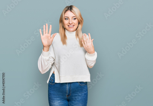 Young caucasian woman wearing casual winter sweater showing and pointing up with fingers number ten while smiling confident and happy.