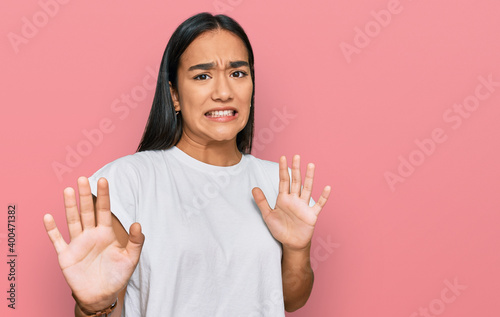 Young asian woman wearing casual white t shirt disgusted expression, displeased and fearful doing disgust face because aversion reaction. with hands raised