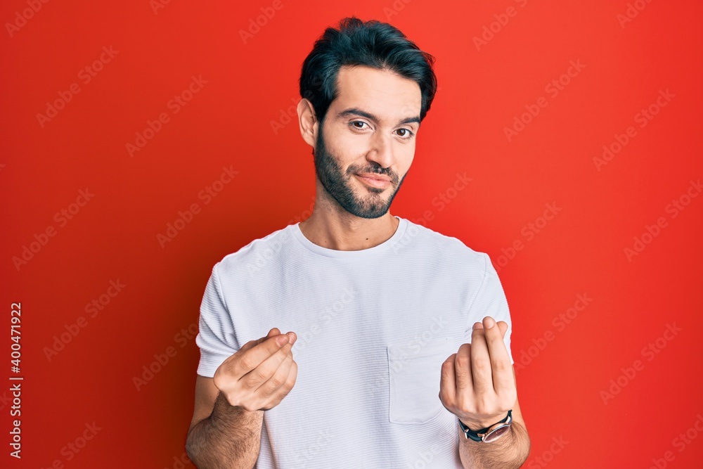 Young hispanic man wearing casual white tshirt doing money gesture with hands, asking for salary payment, millionaire business Young hispanic man wearing casual white tshirt doing money gesture with hands, asking for salary payment, millionaire business
