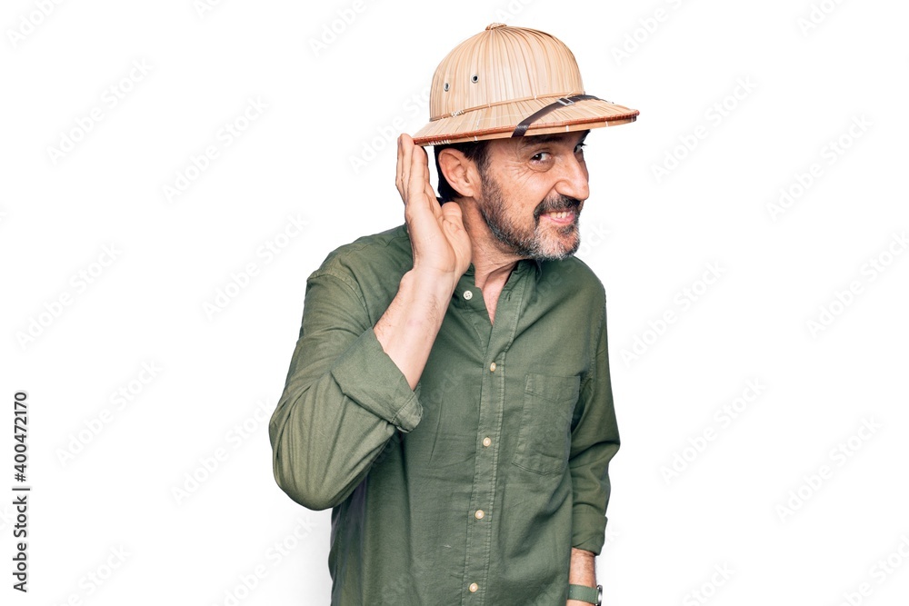 Middle age tourist man on vacation wearing explorer hat over isolated white background smiling with hand over ear listening and hearing to rumor or gossip. Deafness concept. Middle age tourist man on vacation wearing explorer hat over isolated white background smiling with hand over ear listening and hearing to rumor or gossip. Deafness concept.