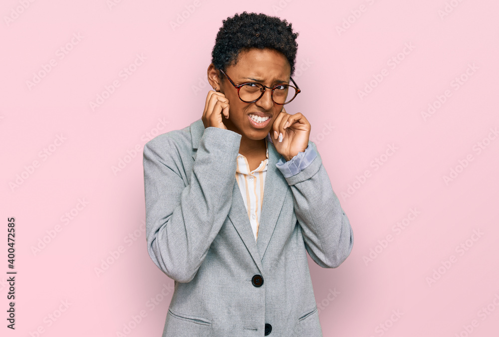 Young african american woman wearing business clothes covering ears with fingers with annoyed expression for the noise of loud music. deaf concept. Young african american woman wearing business clothes covering ears with fingers with annoyed expression for the noise of loud music. deaf concept.