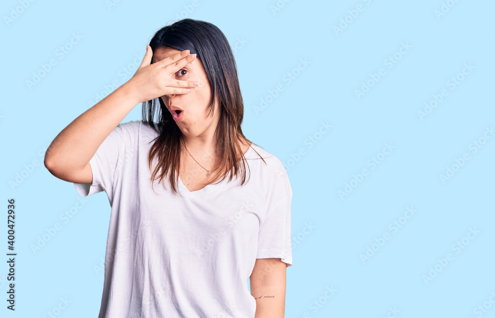 Young beautiful brunette woman wearing casual t-shirt peeking in shock covering face and eyes with hand, looking through fingers with embarrassed expression. Young beautiful brunette woman wearing casual t-shirt peeking in shock covering face and eyes with hand, looking through fingers with embarrassed expression.
