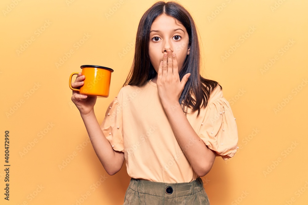 Beautiful child girl holding coffee covering mouth with hand, shocked and afraid for mistake. surprised expression Beautiful child girl holding coffee covering mouth with hand, shocked and afraid for mistake. surprised expression